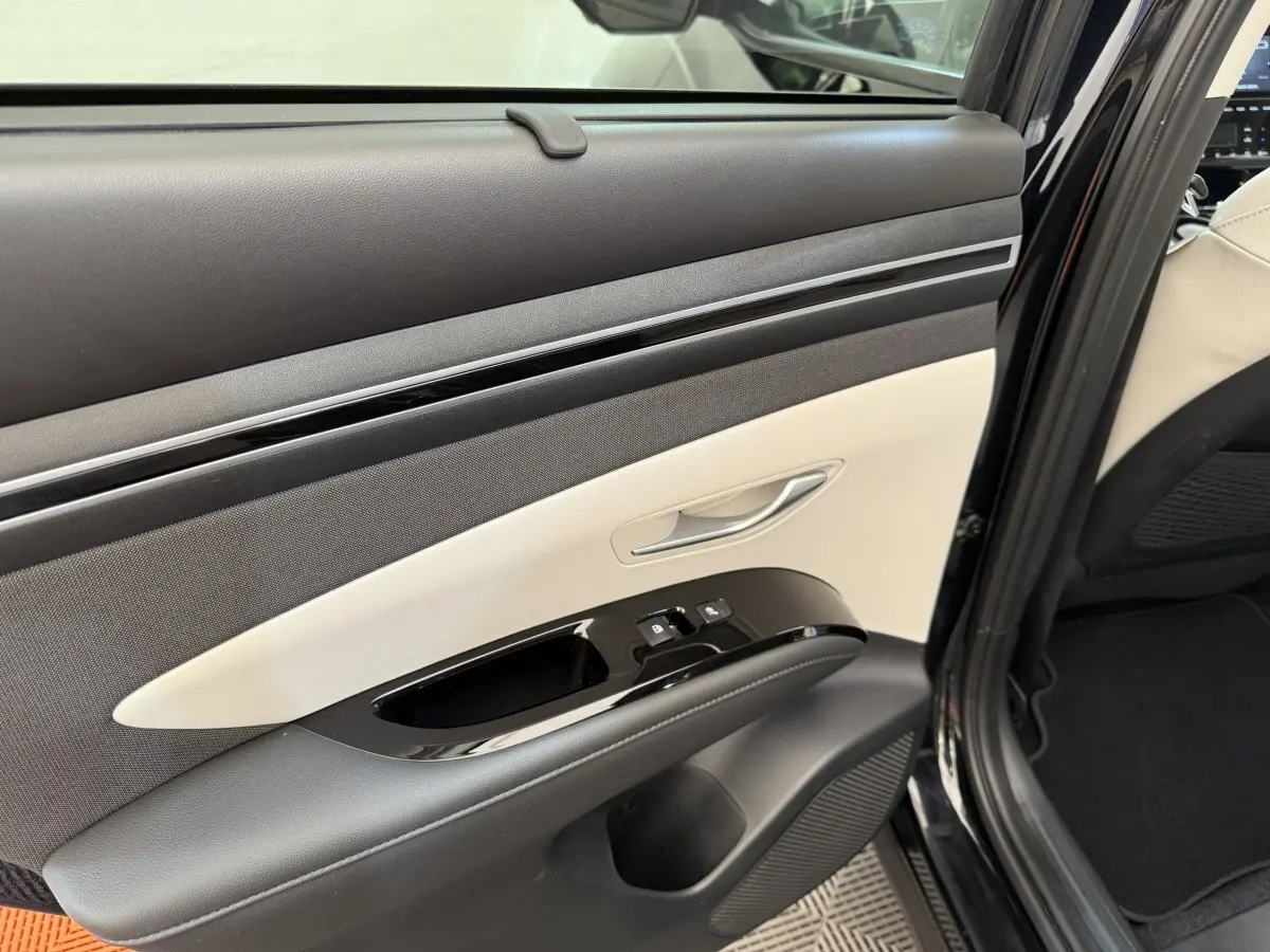 Détail de la porte arrière droite du Hyundai Tucson noir 2022 avec garniture bicolore et commandes de fenêtre.