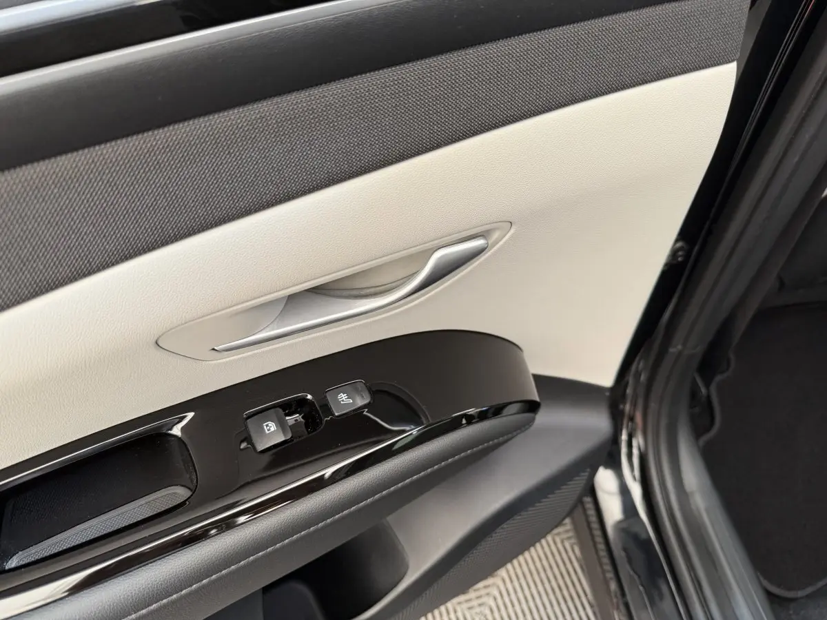 Gros plan sur la porte avant gauche noire du Hyundai Tucson 2022 avec garniture beige et commandes de vitres.