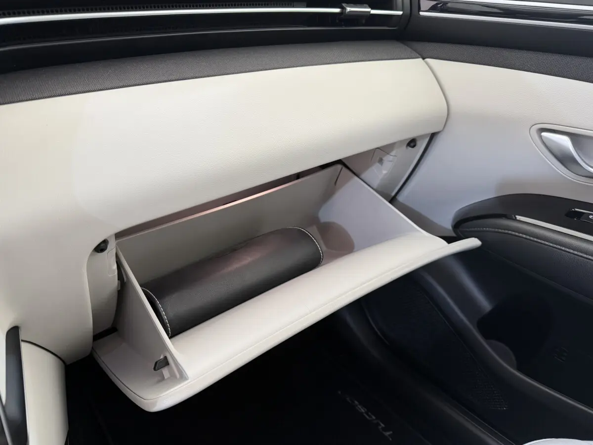 Gros plan sur la boîte à gants beige ouverte côté passager du Hyundai Tucson noir, avec un étui noir à l'intérieur.