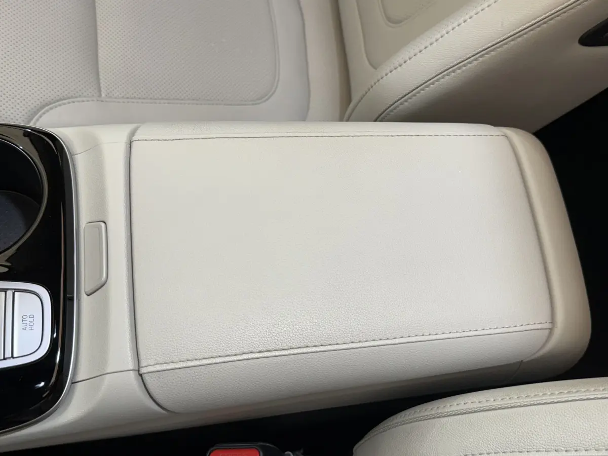 Gros plan sur l'accoudoir central beige clair du Hyundai Tucson 2022, intérieur cuir avec bouton Auto Hold visible.