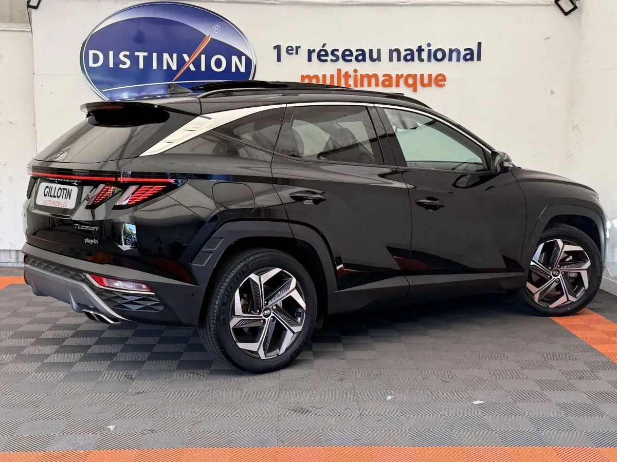 Vue 3/4 arrière côté gauche d'un Hyundai Tucson noir avec jantes alliage et feux arrière LED distinctifs.