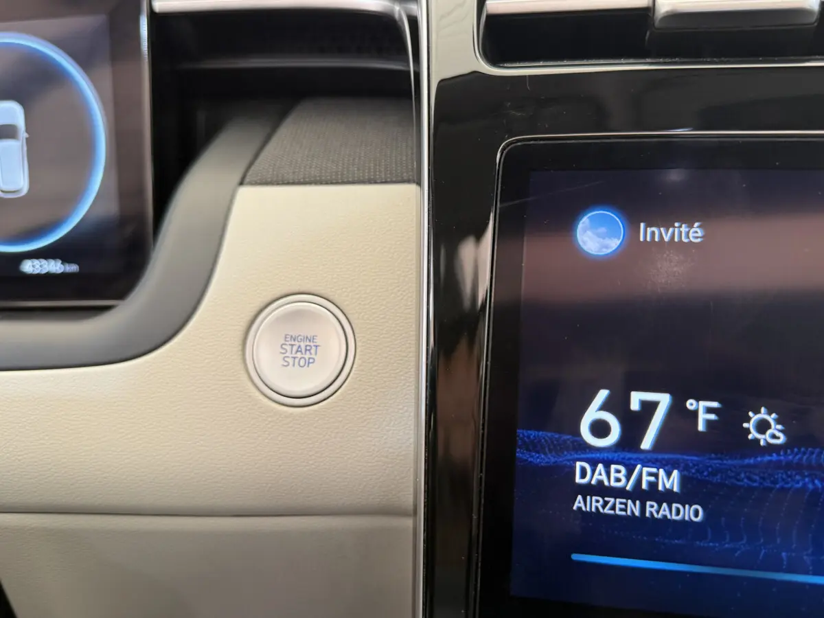 Détail du tableau de bord beige du Hyundai Tucson 2022 avec bouton start/stop et écran tactile affichant la radio.