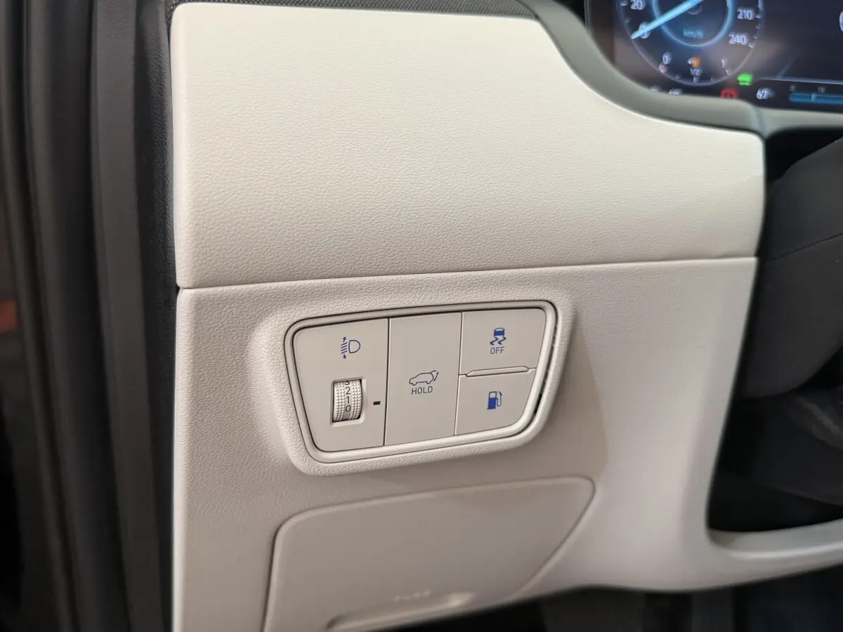 Détail du tableau de bord beige du Hyundai Tucson 2022 avec commandes d'éclairage, maintien, traction et ouverture du coffre.