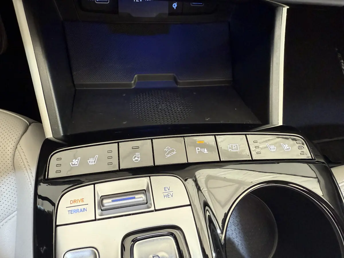 Gros plan sur la console centrale noire brillante du Hyundai Tucson 2022 avec commandes de sièges chauffants et modes de conduite.