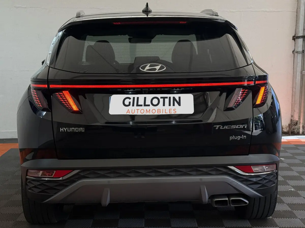 Vue arrière d'un Hyundai Tucson noir avec feux LED allumés et double sortie d'échappement visible.