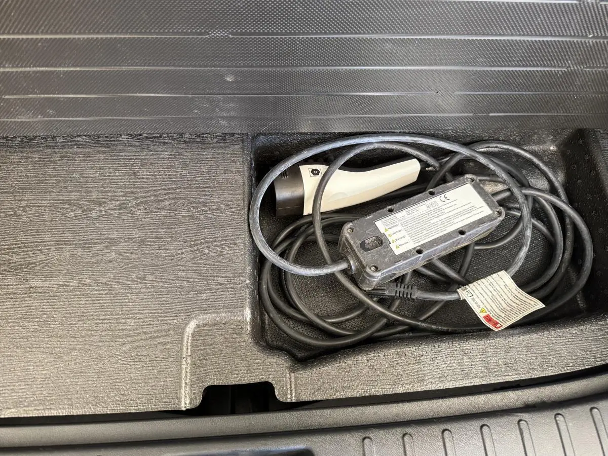 Gros plan sur le câble de recharge rangé dans le coffre du Hyundai Tucson noir hybride rechargeable 2022.