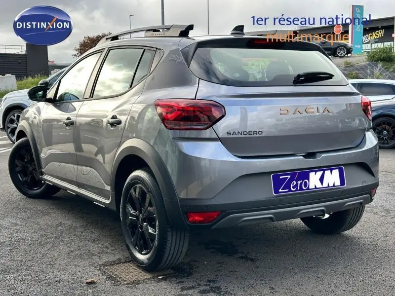Vue 3/4 arrière droite d'une Dacia Sandero Stepway 2025 gris schiste métallisé avec jantes noires et logo distinctif arrière.