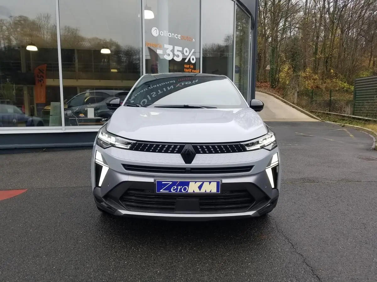 Vue frontale d'un Renault Captur gris Rafale 2025 avec éclairage LED distinctif et plaque "Zéro KM" visible.