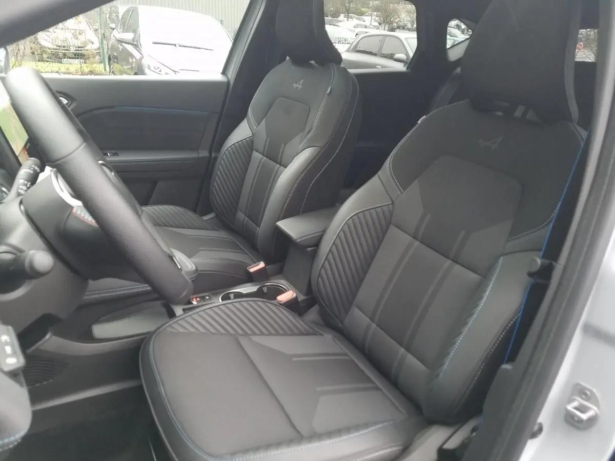 Intérieur du Renault Captur 2025, vue côté conducteur, sièges sport noirs avec surpiqûres bleues et logo Alpine brodé.