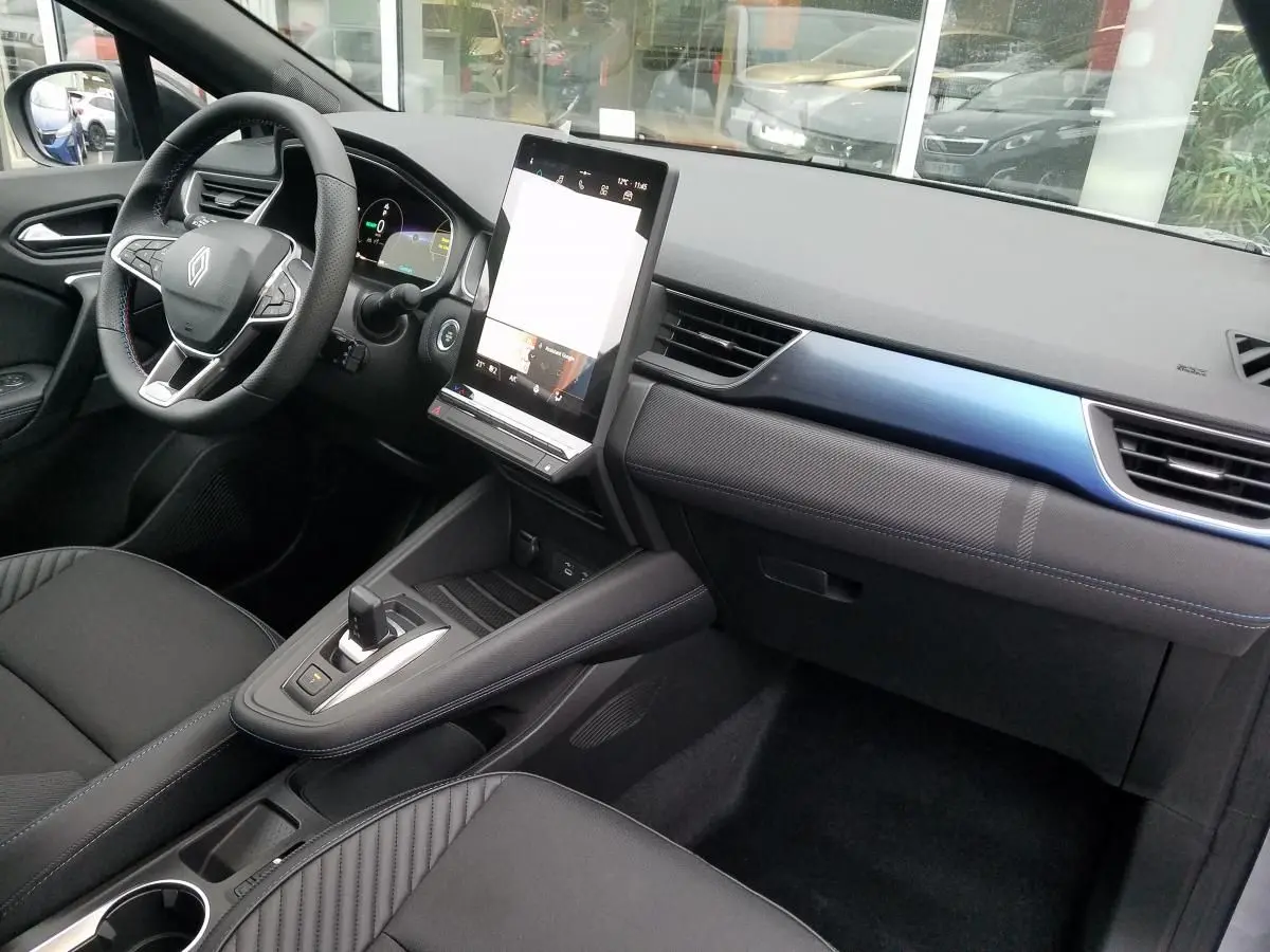 Intérieur avant droit du Renault Captur 2025 avec tableau de bord noir, écran tactile vertical et sellerie noire.