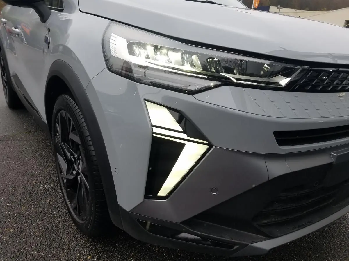 Gros plan sur l'avant gauche du Renault Captur gris Rafale 2025 avec feux LED distinctifs allumés.