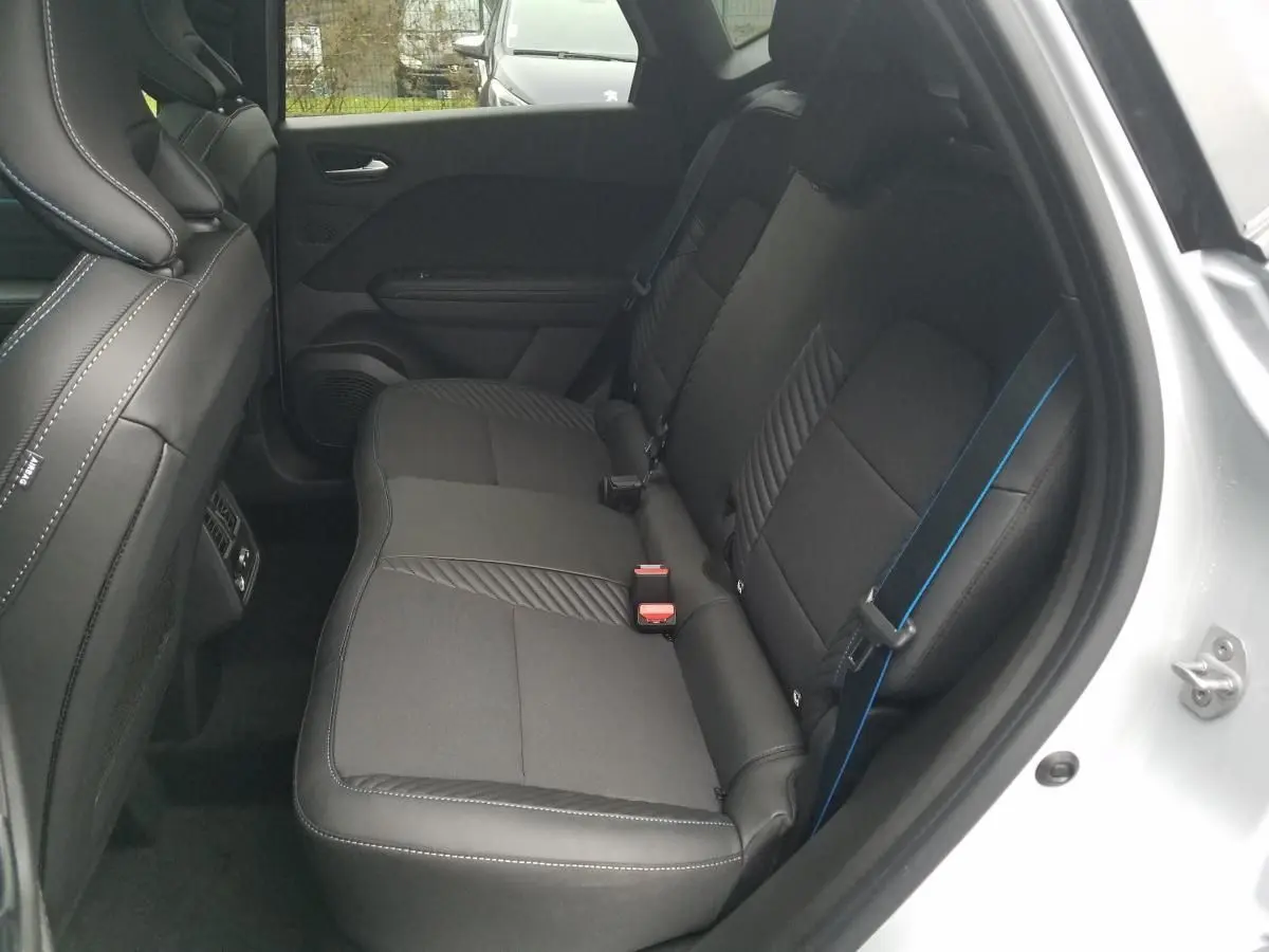 Vue côté droit des sièges arrière noirs avec surpiqûres blanches et ceinture de sécurité bleue du Renault Captur gris Rafale 2025.