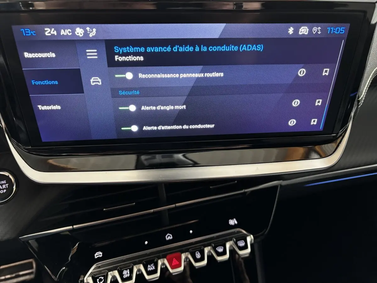 Écran tactile central affichant les aides à la conduite dans l’habitacle noir du Peugeot 208 Hybrid 110 e-DCS6 GT.