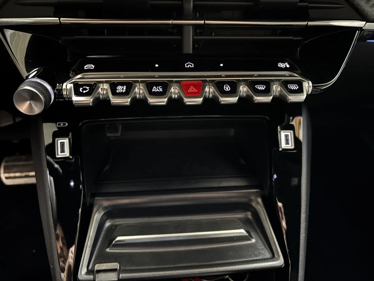 Vue rapprochée de la console centrale noire de la Peugeot 208 Hybrid 110 e-DCS6 GT avec boutons métalliques et écran tactile.