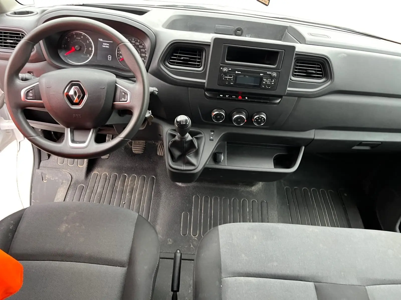 Vue intérieure du tableau de bord et volant noir du Renault Master Châssis Cabine blanc, avec levier de vitesses manuel et sièges tissus noirs.