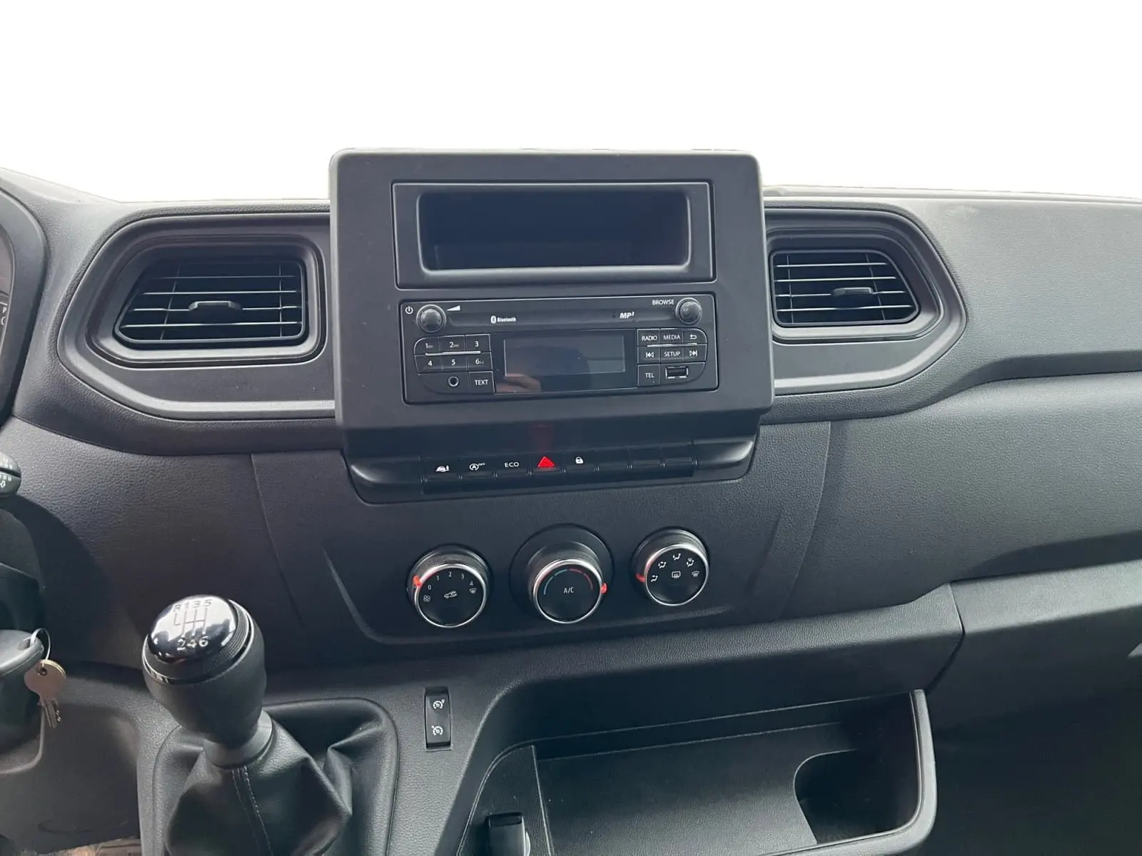 Vue intérieure centrée sur la console centrale du Renault Master Châssis Cabine 2023 avec boîte manuelle et commandes climatisation.
