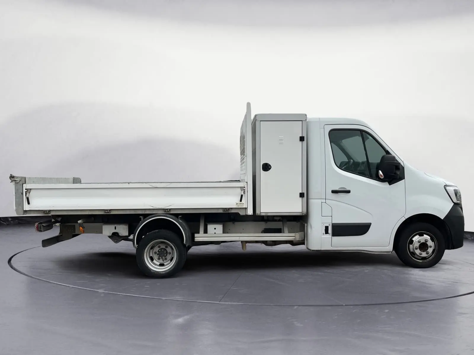 Profil droit d’un Renault Master Châssis Cabine blanc 2023 avec benne, coffre latéral et roues jumelées arrière.