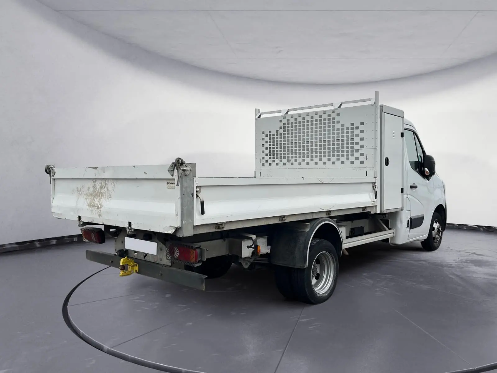 Vue 3/4 arrière droite d’un Renault Master blanc avec benne et coffre, roues jumelées et hayon arrière sali.