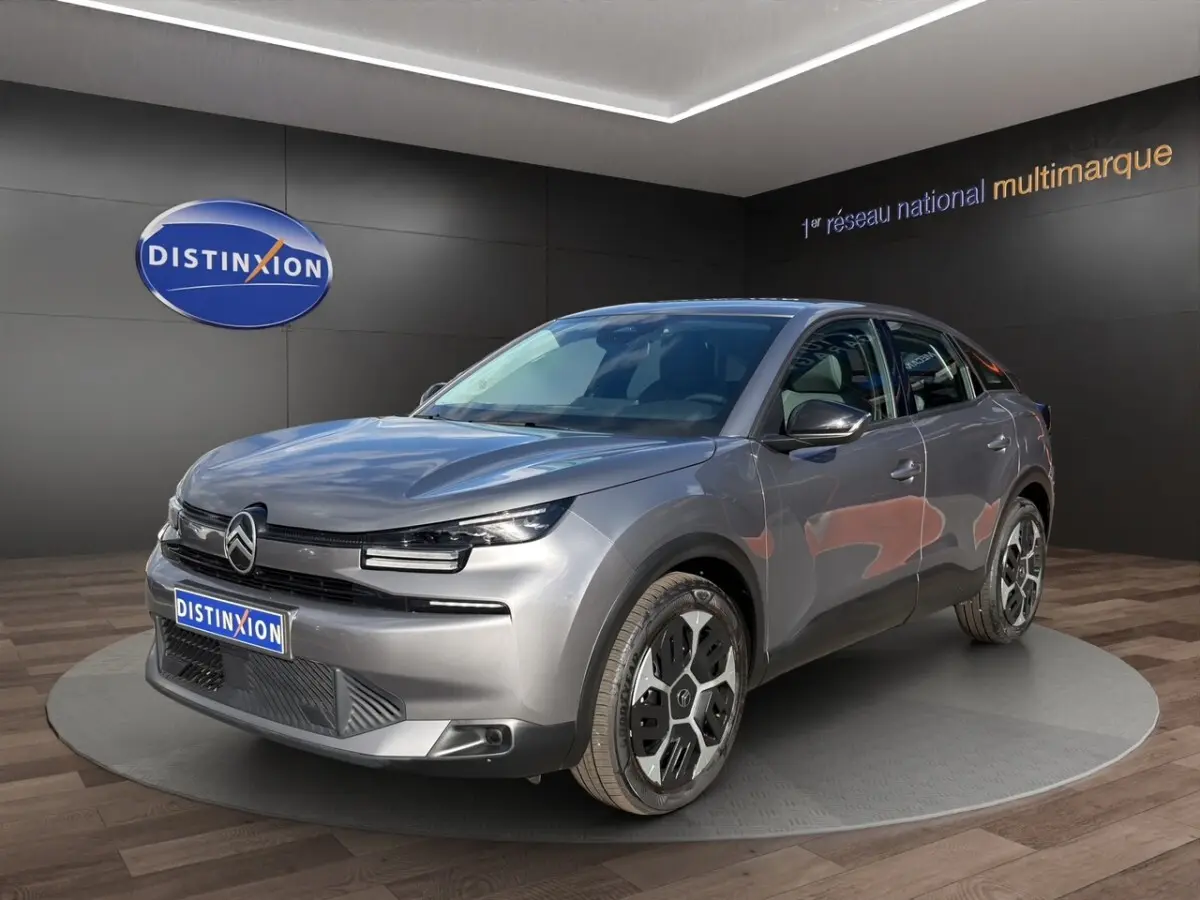 Citroën C4 hybride gris foncé vue 3/4 avant droit, avec phares LED et jantes distinctives en exposition showroom.