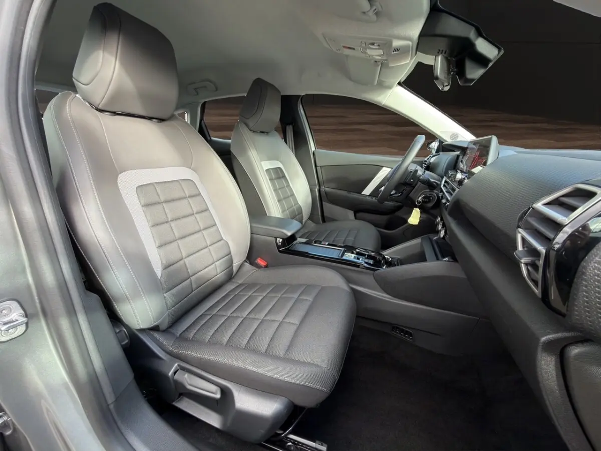 Vue intérieure côté conducteur de la Citroën C4 hybride 2025, sièges gris et tableau de bord moderne avec écran tactile.