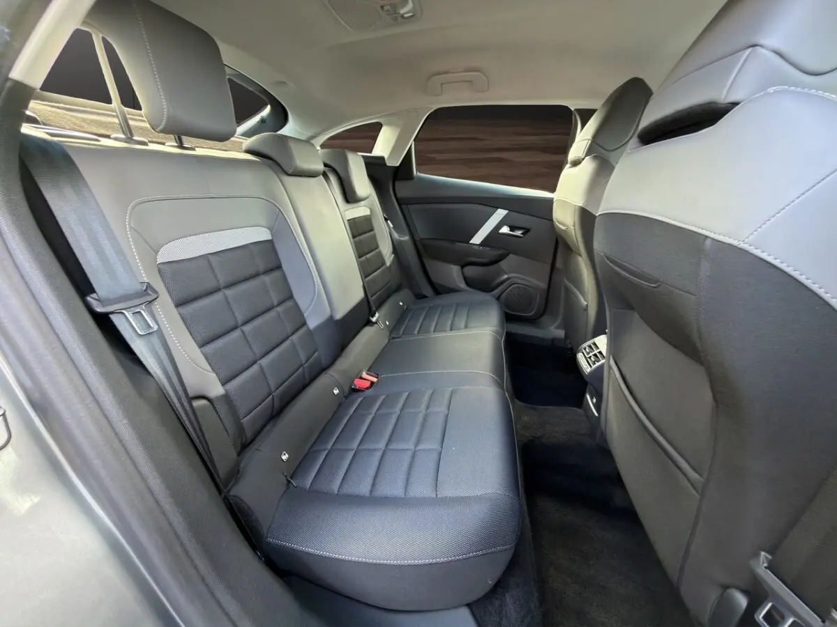 Vue intérieure arrière côté droit de la banquette noire et grise de la Citroën C4 hybride 2025 avec ceintures et appuie-têtes.