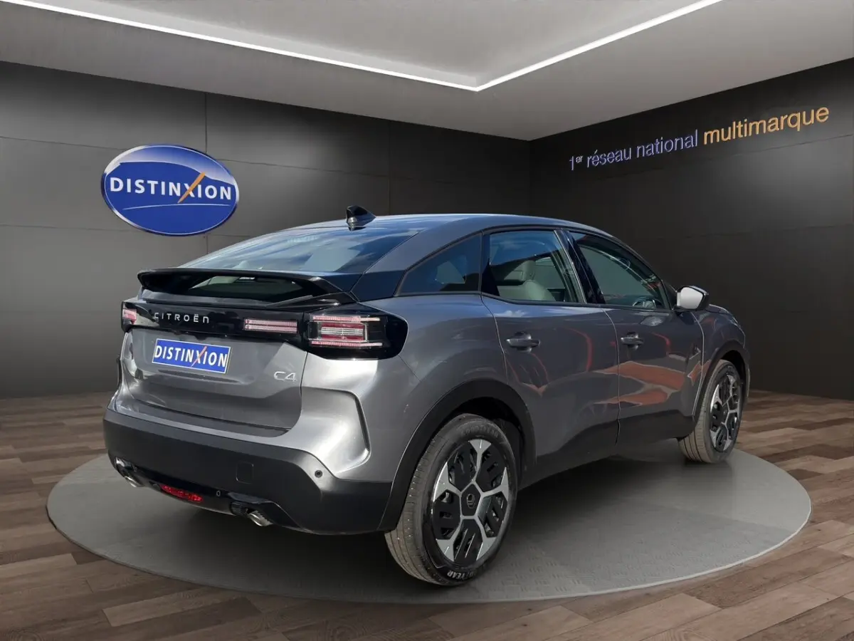 Vue 3/4 arrière droite d'une Citroën C4 hybride gris foncé avec jantes distinctives et toit noir brillant.