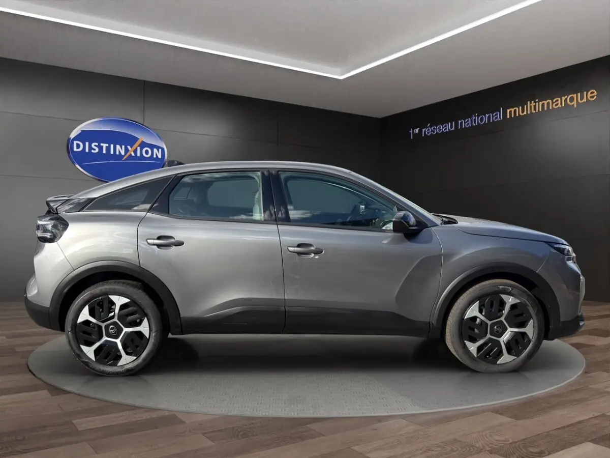 Profil droit d'une Citroën C4 hybride gris foncé avec jantes au design moderne, exposée en showroom.