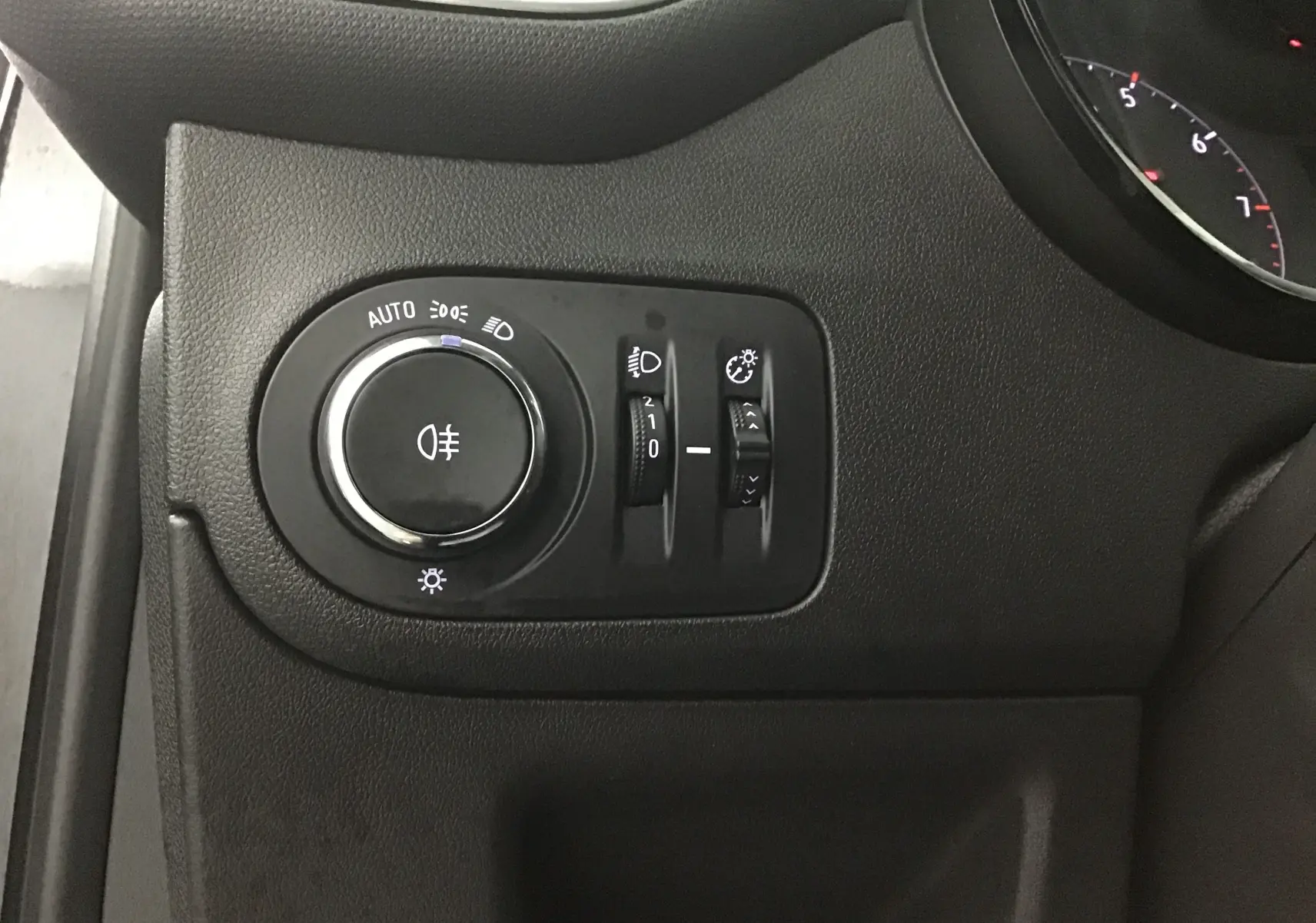 Gros plan sur les commandes d'éclairage noires à gauche du tableau de bord de l'Opel Crossland noir 2022.