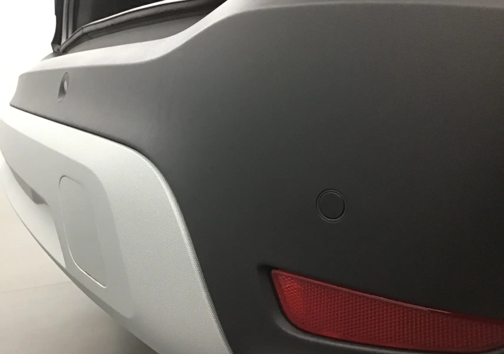 Gros plan sur le pare-chocs arrière noir de l'Opel Crossland 2022 avec feu rouge et capteur de recul intégré.