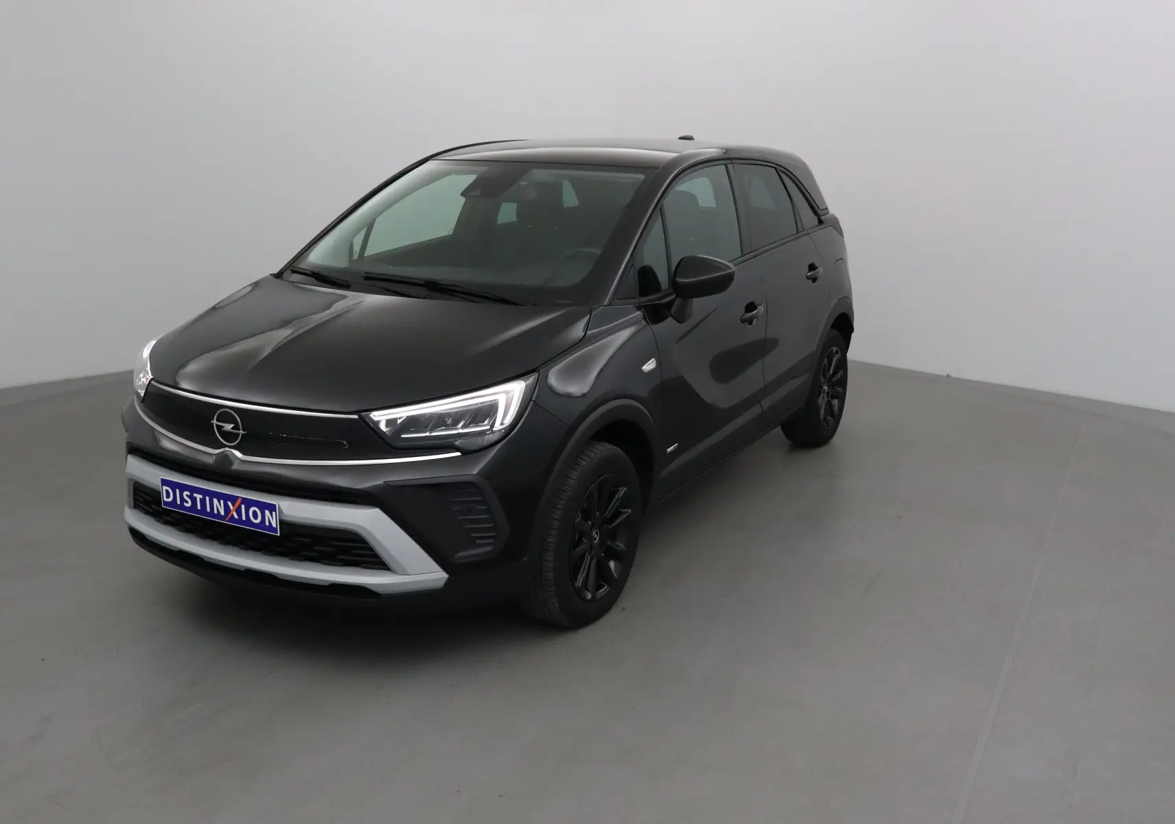 Opel Crossland noir vue 3/4 avant droit, avec calandre moderne et jantes noires dans un studio gris.