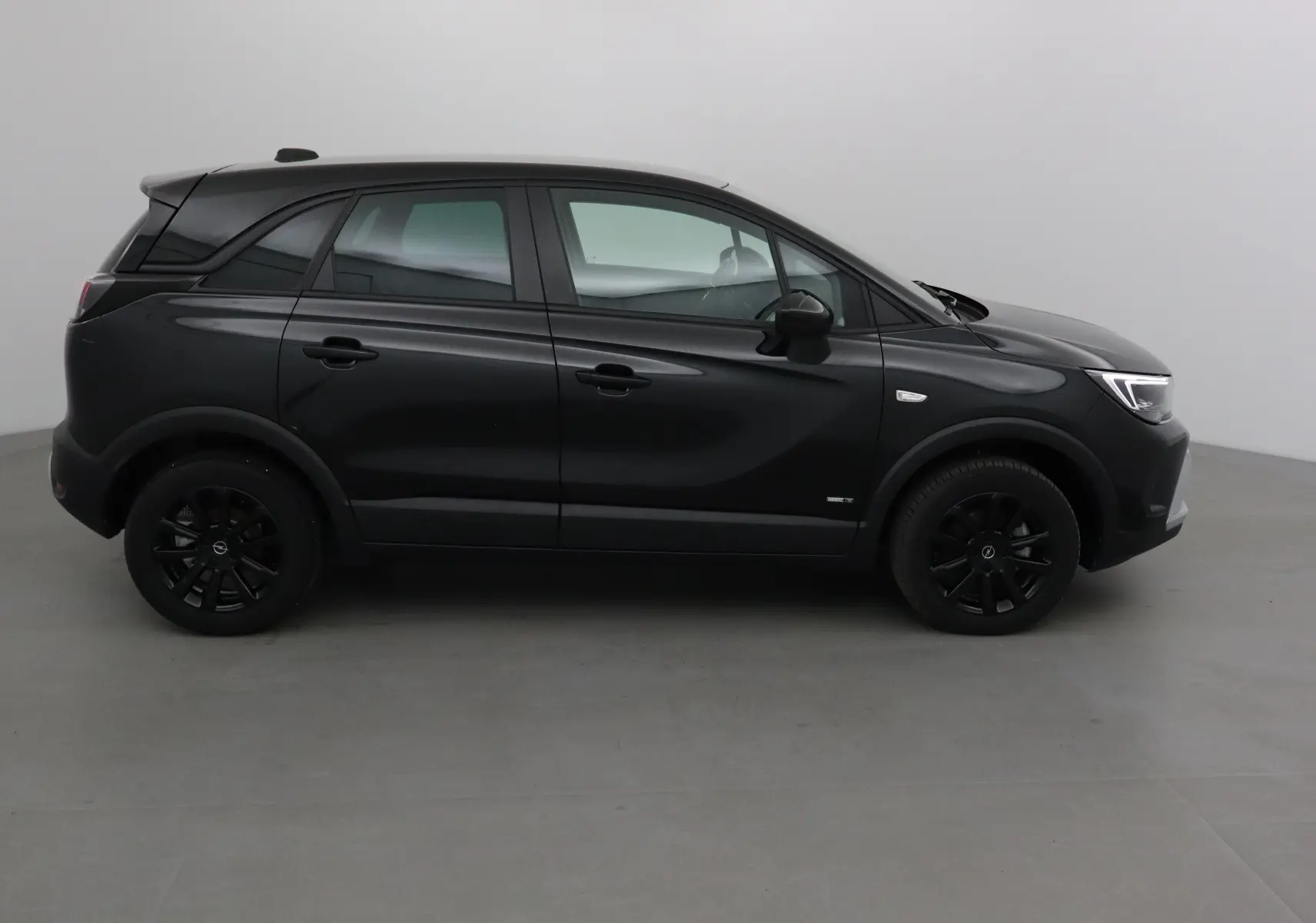 Opel Crossland noir en vue profil côté gauche, mettant en valeur ses jantes noires et lignes épurées.