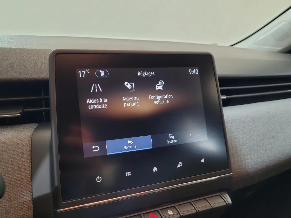 Écran tactile central affichant les réglages d’aides à la conduite dans l’habitacle clair de la Renault Clio bleu.