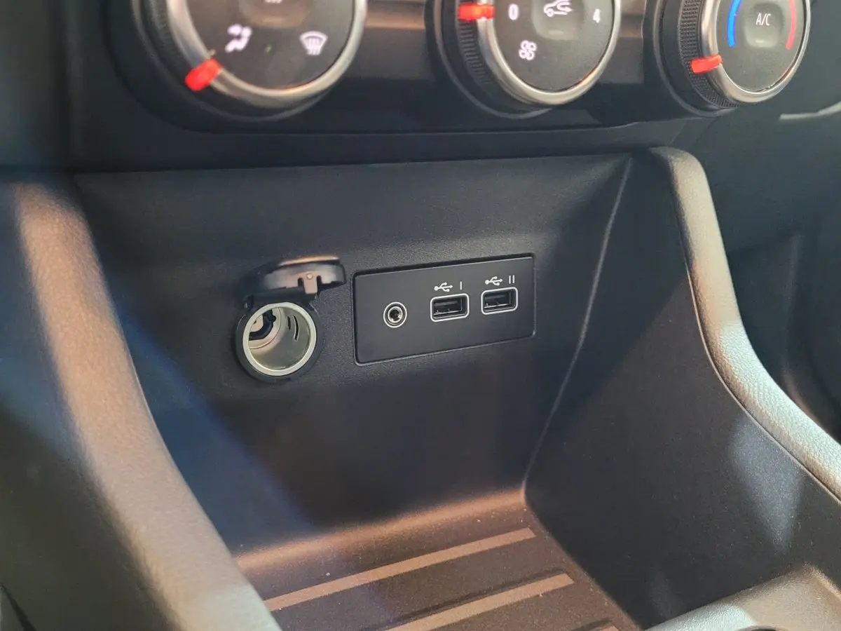 Vue rapprochée de la console centrale noire de la Renault Clio bleu, montrant prises USB et allume-cigare ouverts.