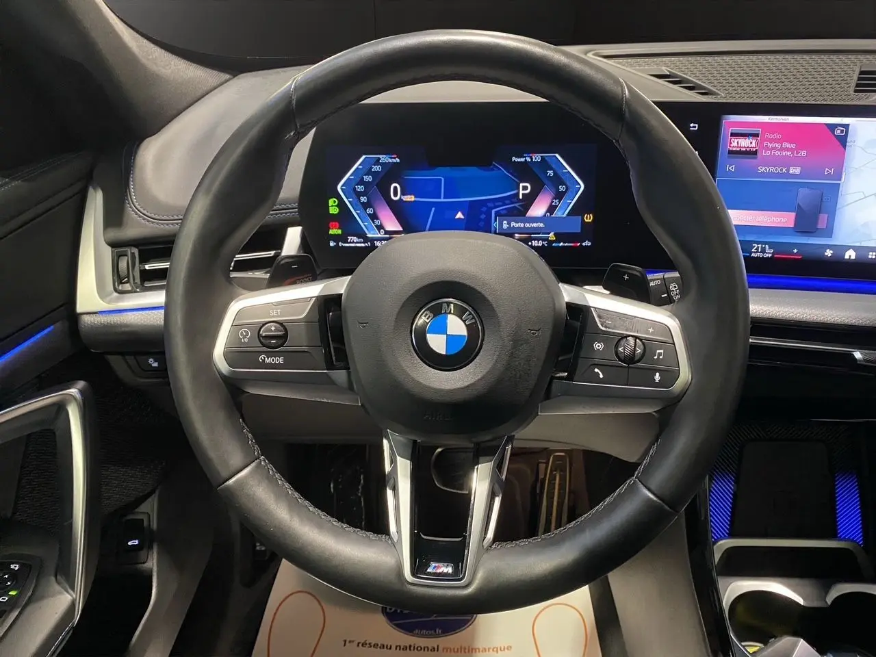 Vue rapprochée du volant cuir noir BMW X1 XDRIVE 20D M SPORT 2025 avec tableau de bord numérique et écran tactile.