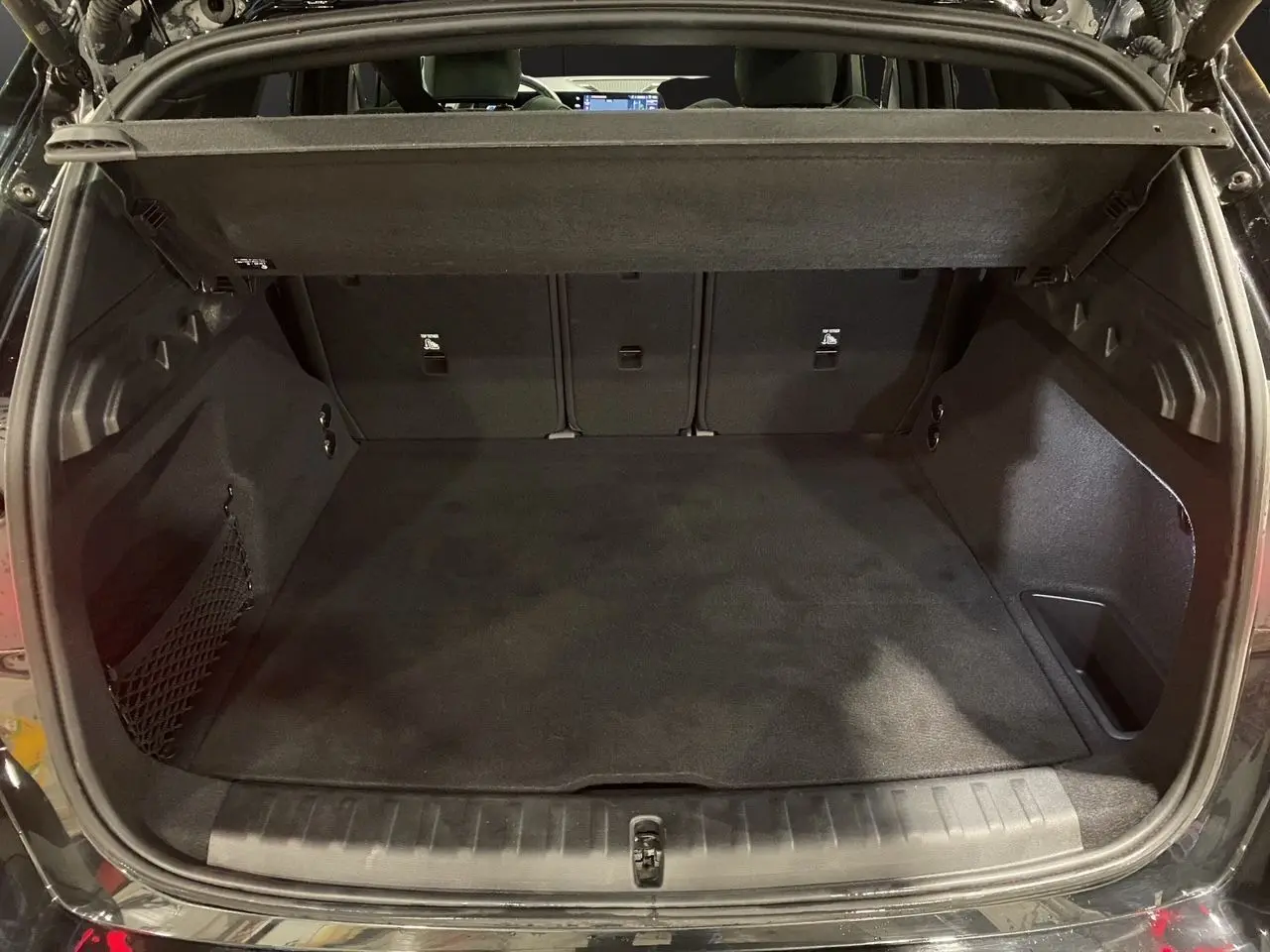 Coffre ouvert en vue arrière d'un BMW X1 noir Saphir, montrant un espace de chargement propre et spacieux.