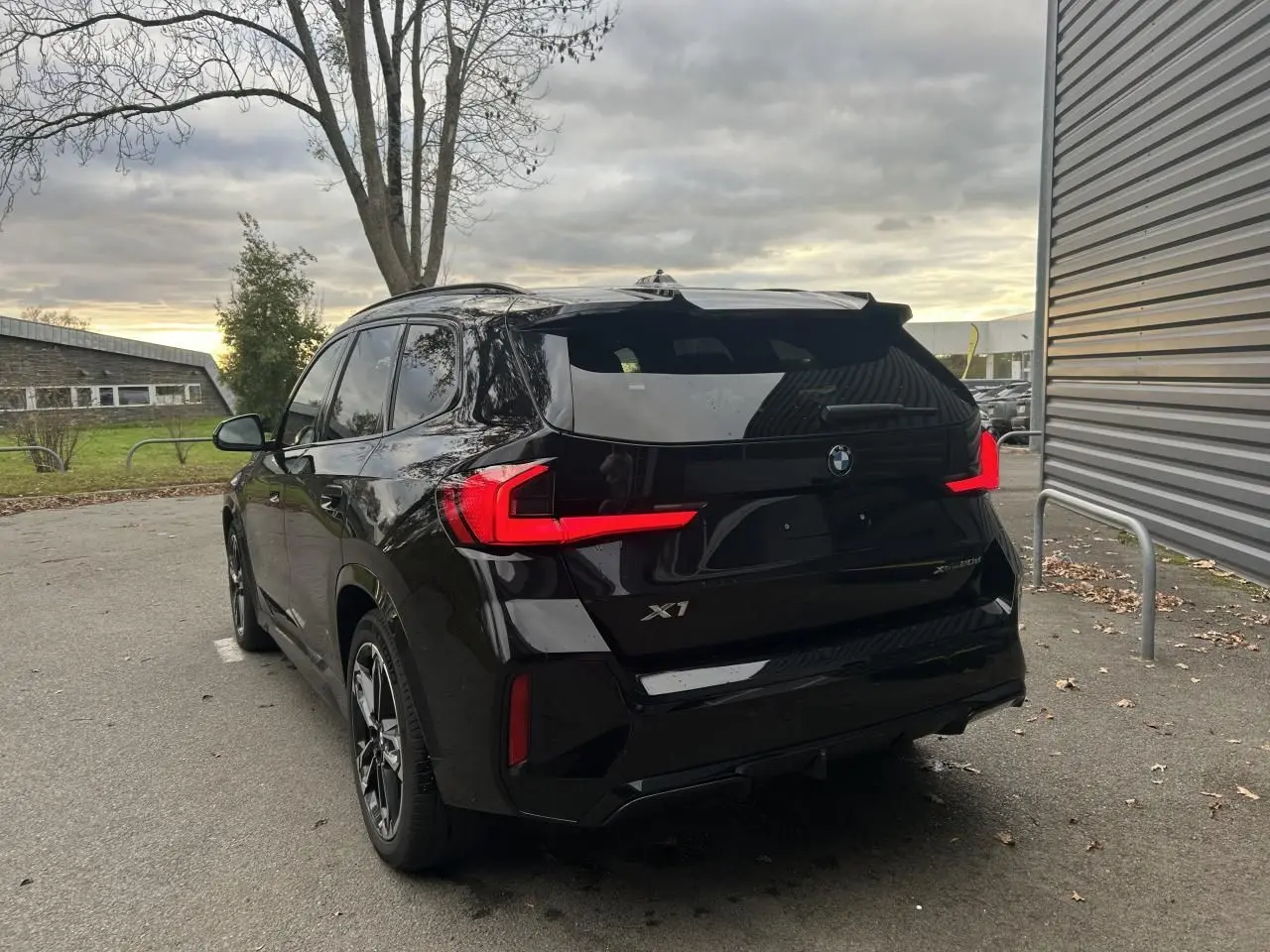 Vue 3/4 arrière gauche d'un BMW X1 2025 noir Saphir avec feux arrière LED et jantes M Sport.