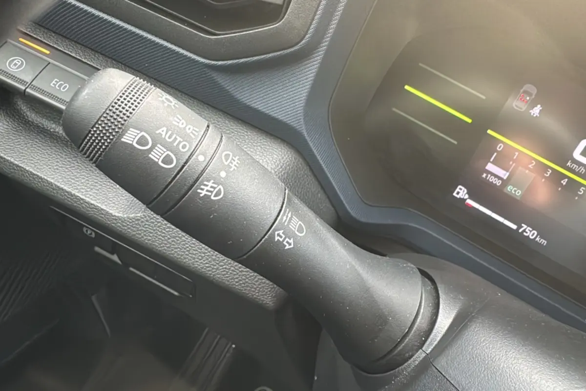 Gros plan sur la commande des feux et clignotants du tableau de bord du Dacia Duster 2025, intérieur noir.