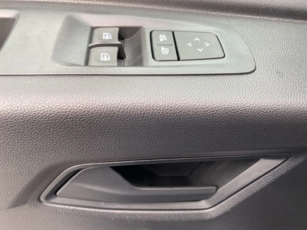 Poignée de porte intérieure côté conducteur avec commandes électriques des vitres et réglage des rétroviseurs du Renault Master blanc.