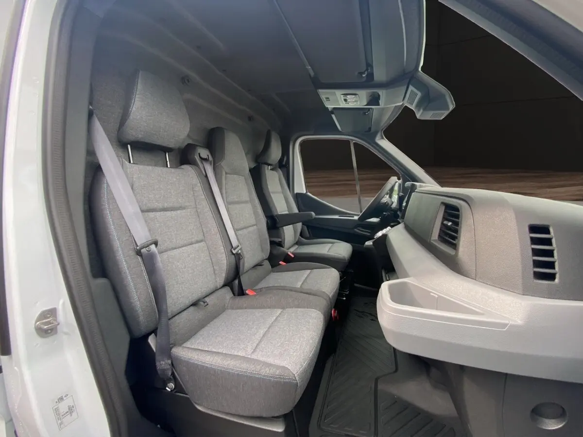 Vue intérieure côté gauche du Renault Master blanc 2026, montrant les sièges avant en tissu gris et le tableau de bord.