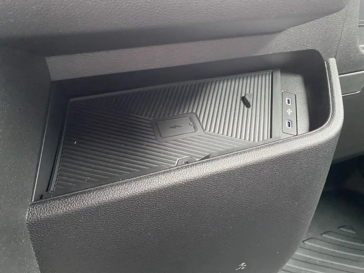 Gros plan sur le rangement central noir avec zone de recharge par induction et ports USB dans Renault Master blanc.