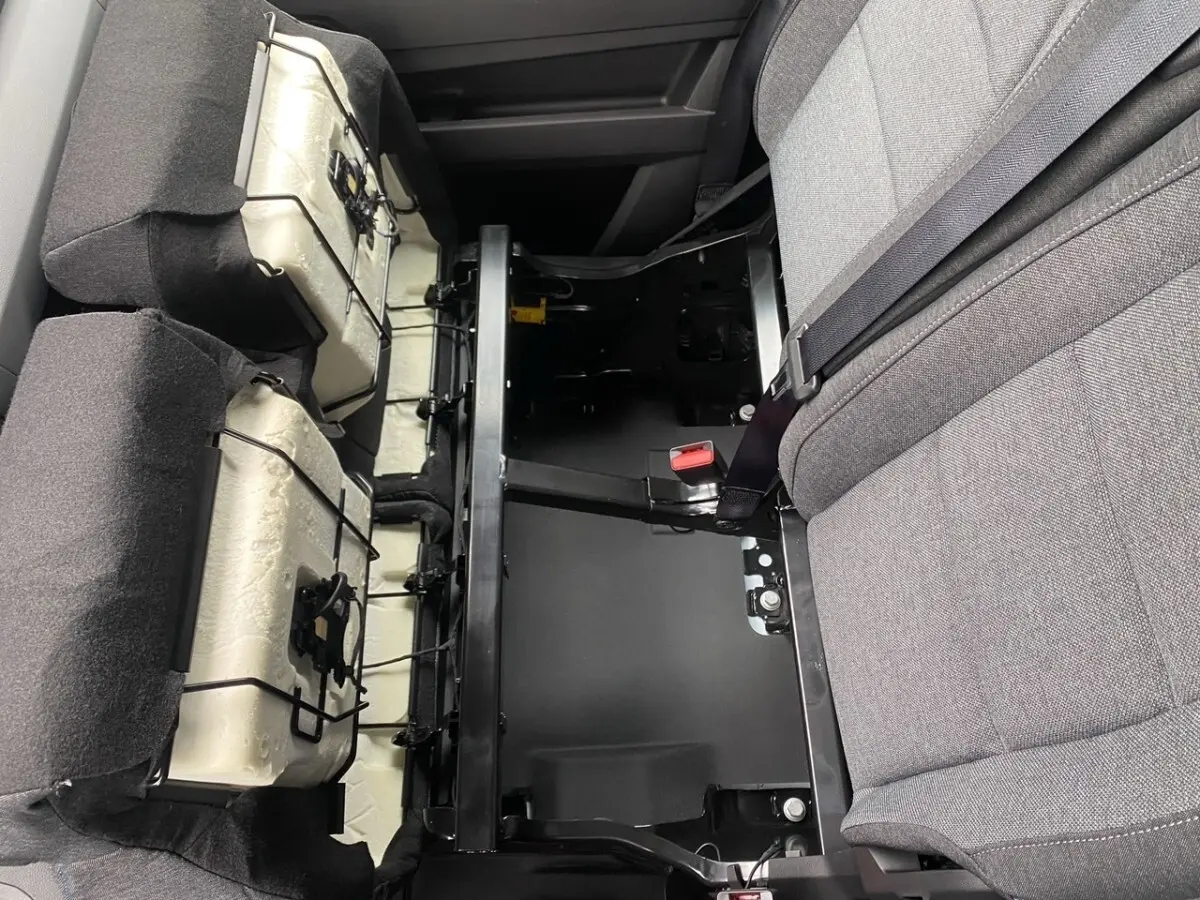 Vue rapprochée de l'intérieur arrière du Renault Master blanc, montrant la structure métallique et les sièges gris partiellement relevés.