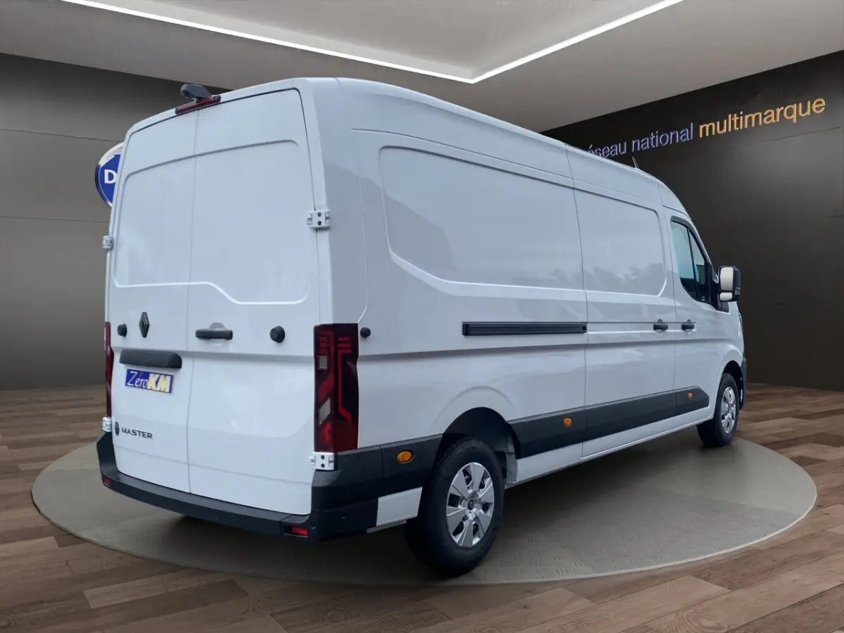 Renault Master blanc en vue 3/4 arrière droit, fourgon utilitaire avec feux arrière LED et bandes latérales noires.