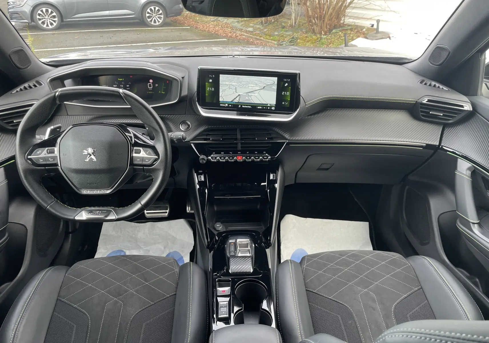 Vue intérieure avant du Peugeot 2008 GT 2022 avec tableau de bord numérique, écran central tactile et sièges en cuir noir avec surpiqûres vertes.