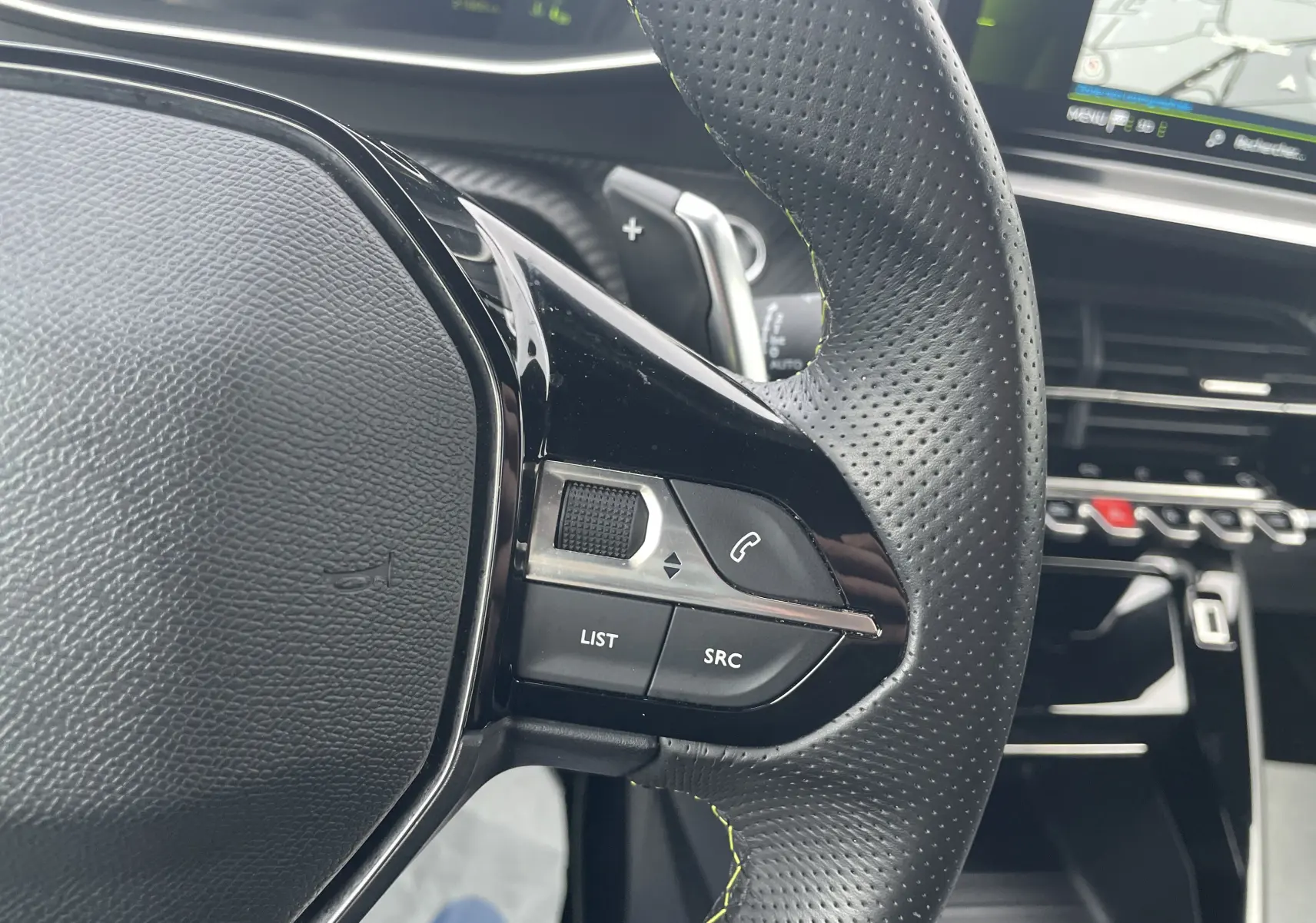 Gros plan sur le volant perforé noir avec commandes intégrées du Peugeot 2008 GT 2022, intérieur moderne et écran tactile visible.