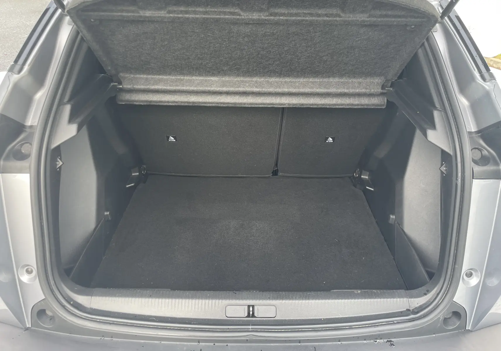 Coffre ouvert vu de l'arrière d'un Peugeot 2008 gris Artense, montrant un espace de chargement vide et propre.