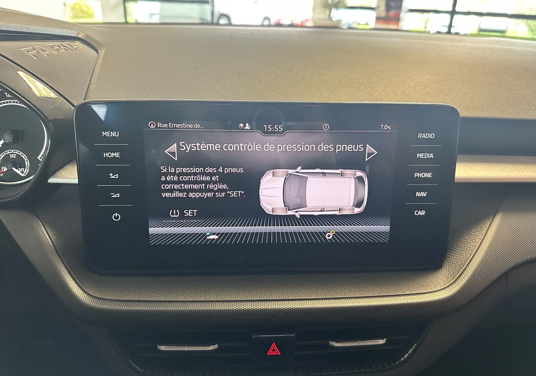 Vue intérieure du tableau de bord de la Skoda Fabia 2023 gris argent, écran central affichant le contrôle de pression des pneus.