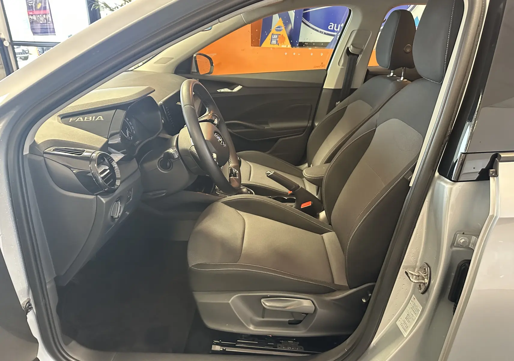 Intérieur côté conducteur de la Skoda Fabia Ambition 2023 gris argent, sièges tissu gris et tableau de bord avec logo Fabia.