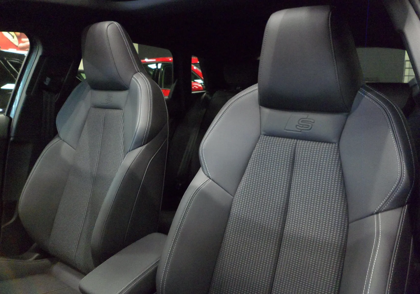 Gros plan sur les sièges avant en cuir noir avec surpiqûres blanches et logo S de l'Audi A3 Sportback 2025.