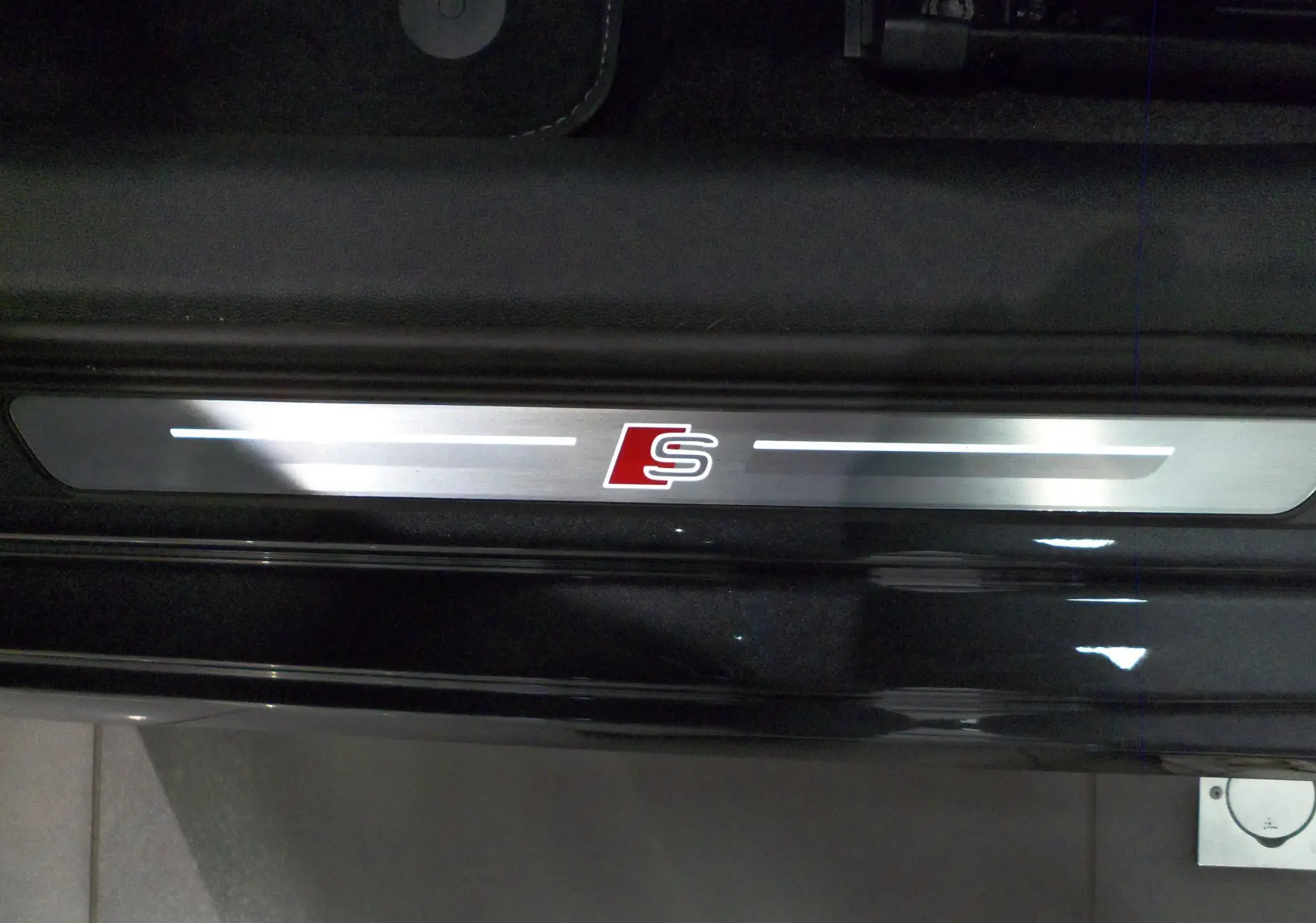 Gros plan sur la plaque de seuil de porte avec logo S rouge, intérieur noir de l'Audi A3 Sportback 2025.