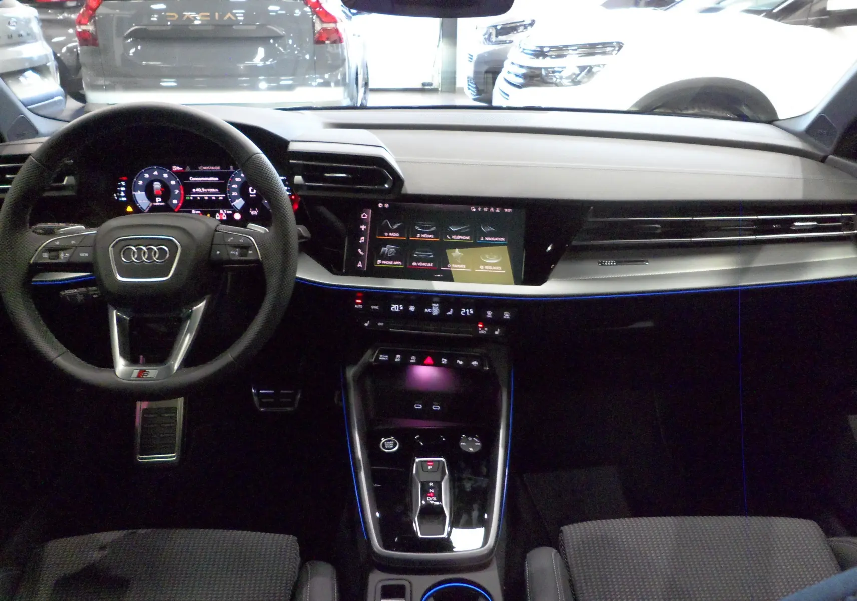 Intérieur Audi A3 Sportback 2025 vu de face, tableau de bord moderne avec éclairage d'ambiance bleu et écran tactile central.